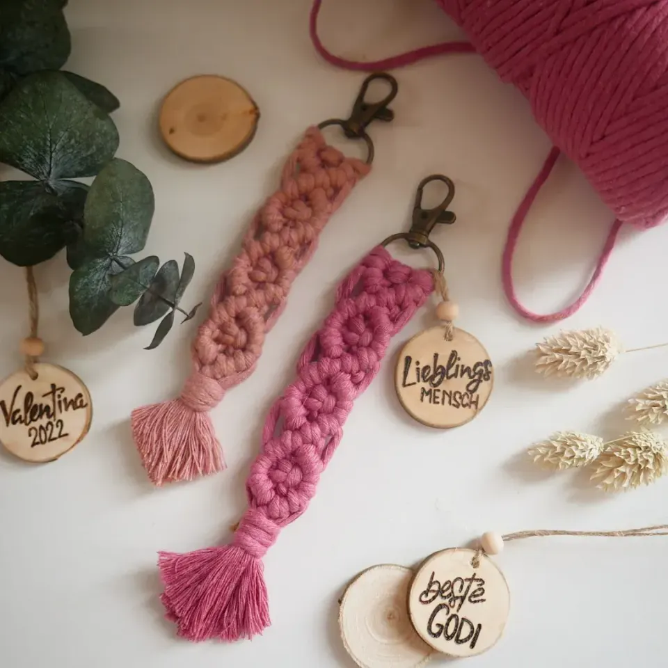 Zwei Makramee-Schlüsselanhänger in Rosa mit Holzscheiben, beschriftet mit Namen