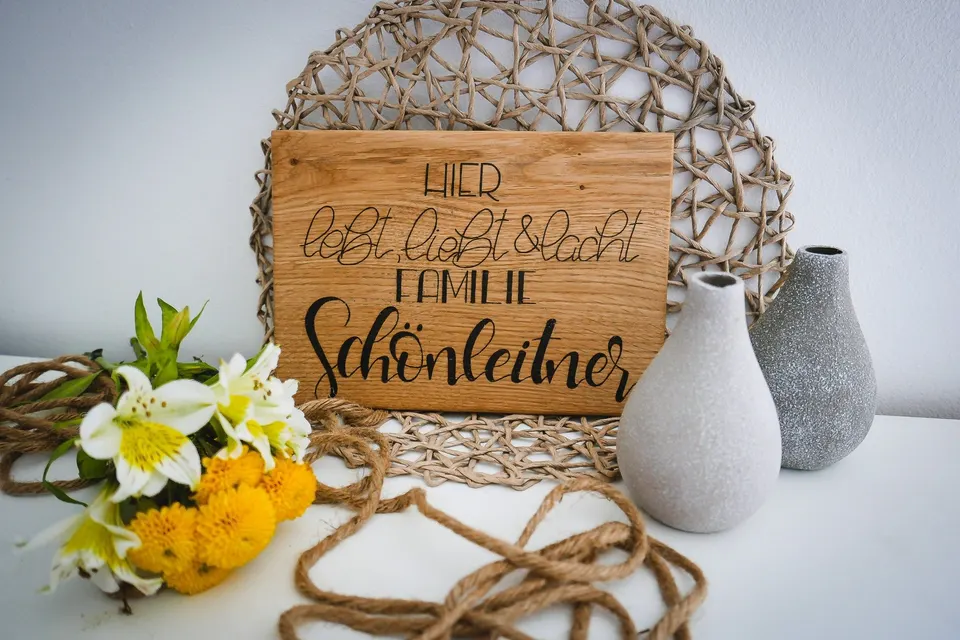 Türschild aus Holz für Familie Schönleitner, aufgestellt neben einer Vase