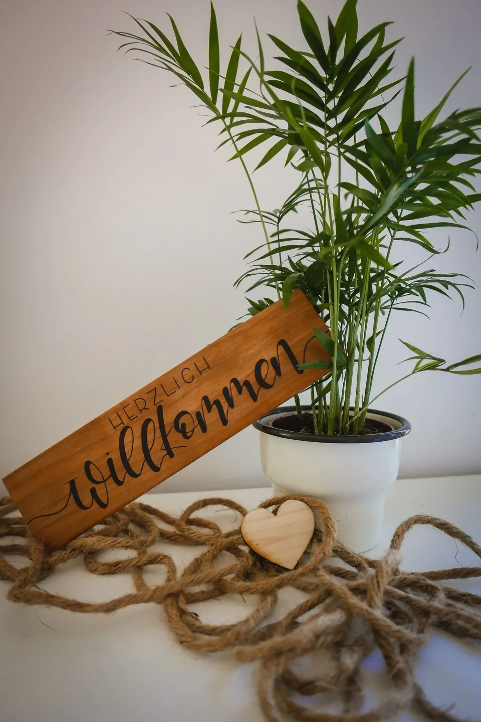 Längliches Holzschild mit dem Schriftzug Herzlich Willkommen
