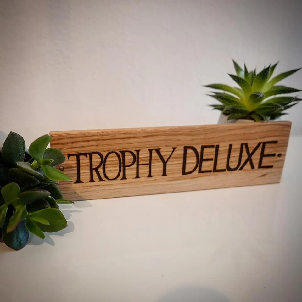Holzschild mit dem eingebrannten Schriftzug Trophy Deluxe