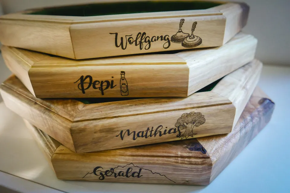 Gestapelte Würfelteller aus Holz, auf jedem ein Name mit kleinem Motiv