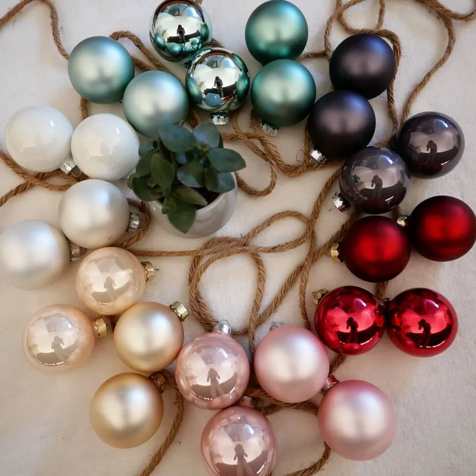Viele Christbaumkugeln in Rot, Rosa, Grün und Silber vor dem Beschriften