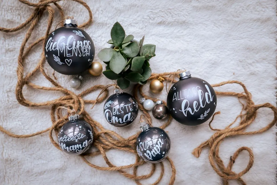 Matte, dunkle Christbaumkugeln mit weißer Schrift: Beste Oma, Alltagsheld, Lieblingsmensch