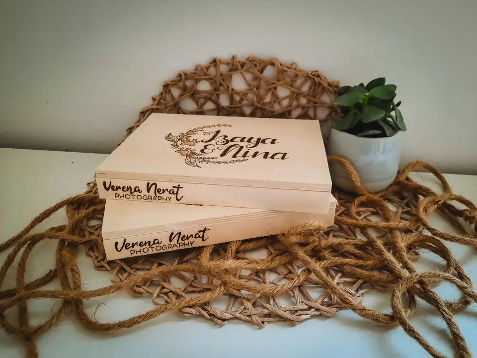 Holzboxen mit Blumenkranz und den Namen Izaya & Nina, auf der Kante das Logo einer Fotografin