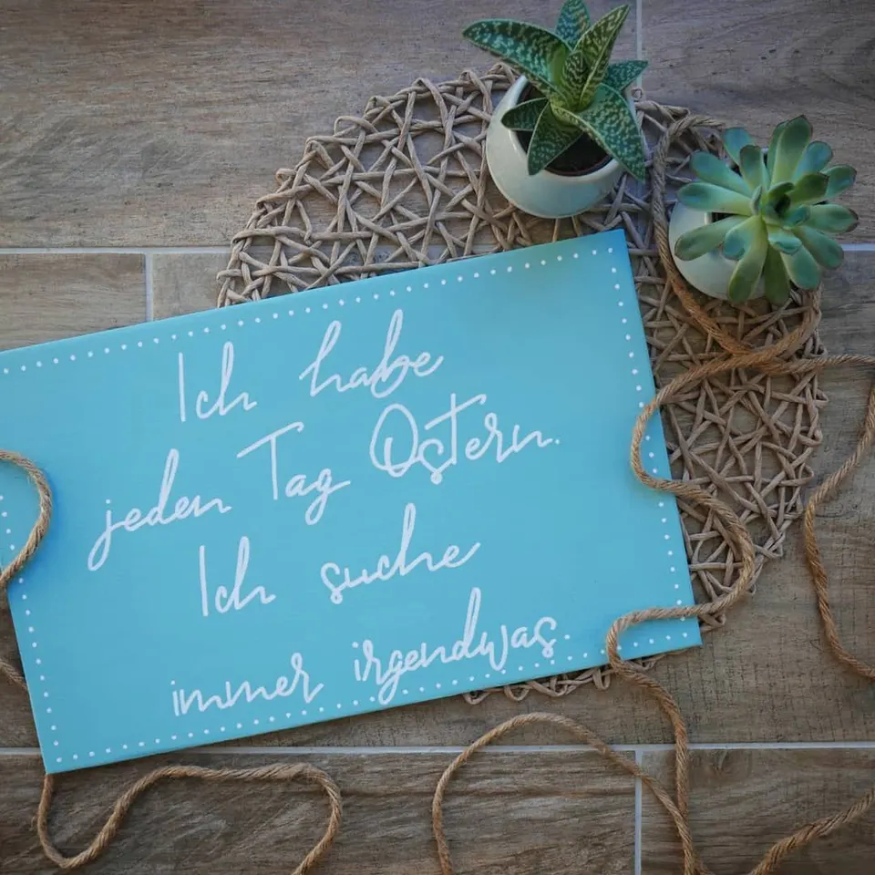 Türkis bemaltes Holzschild mit dem Spruch Ich habe jeden Tag Ostern, ich suche immer irgendwas