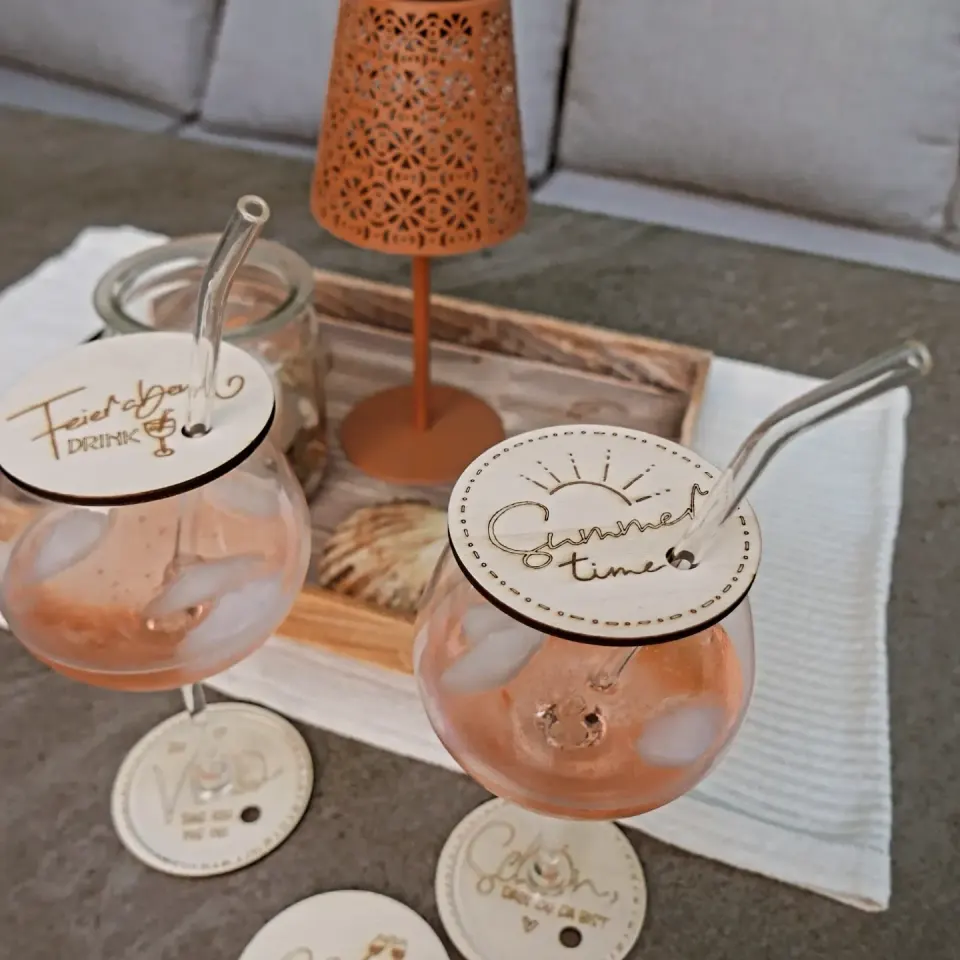 Zwei Gläser mit Holzdeckeln und Glasstrohhalm, auf den Deckeln die Schriftzüge Feierabend Drink und Summer Time
