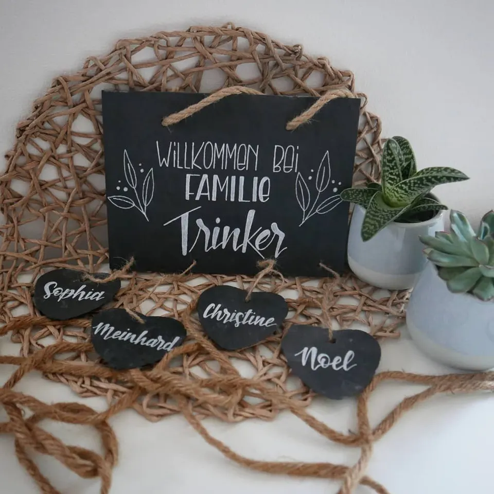 Schiefertafel Willkommen bei Familie Trinker, davor Schieferherzen mit den Vornamen