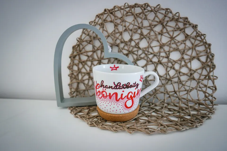 Tasse mit rotem Schriftzug und kleiner Krone