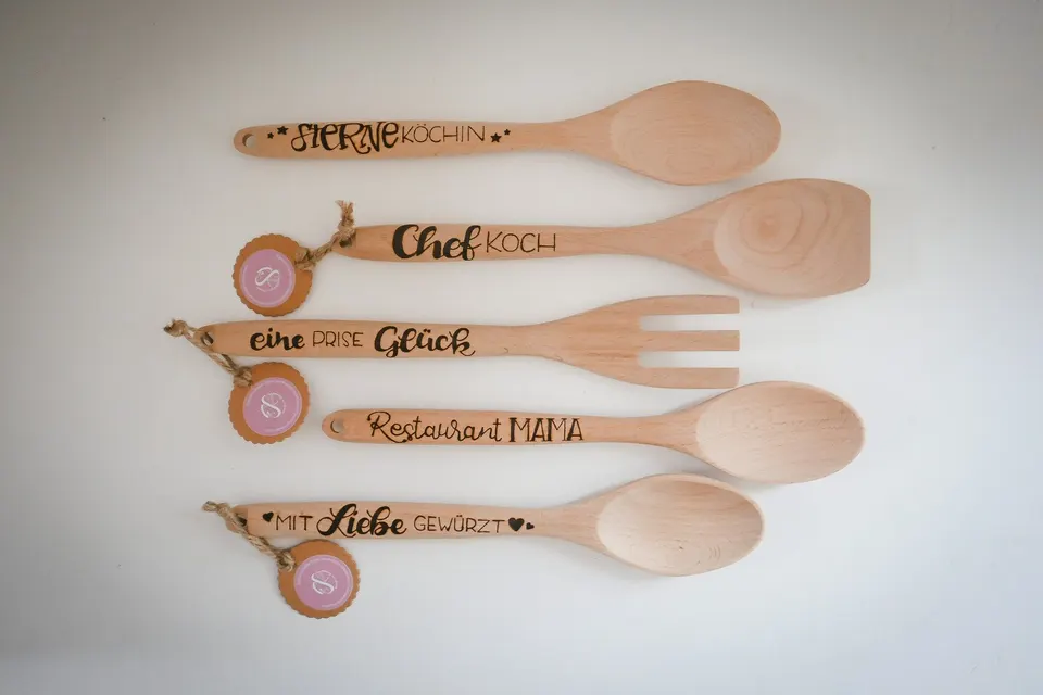 Fünf Kochlöffel und Pfannenwender mit eingebrannten Sprüchen wie Chefkoch und Eine Prise Glück